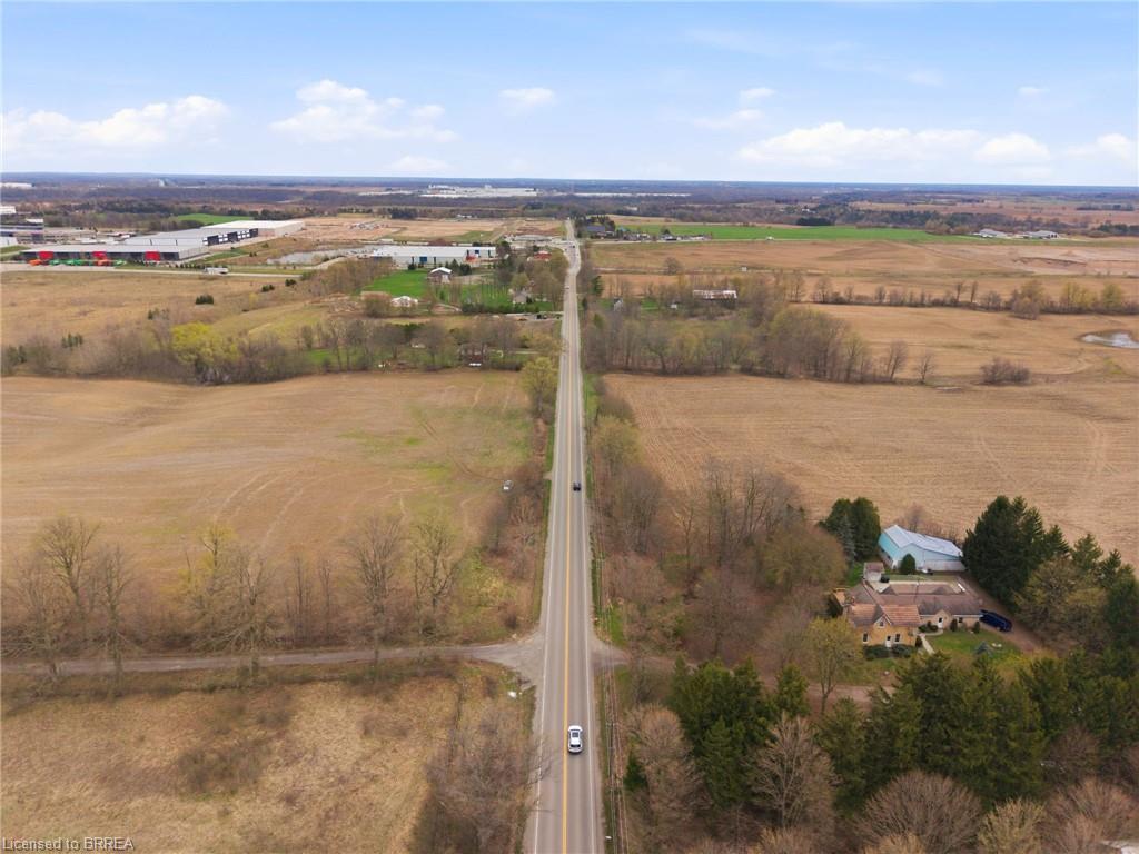Expansive rural landscape featuring a long road, surrounding fields, and scattered trees
