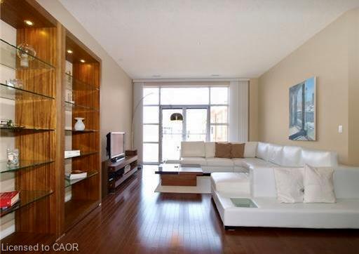 Wood-finish flooring, built-in shelving with glass shelves, recessed lighting, expansive window with exterior access, and a vaulted ceiling