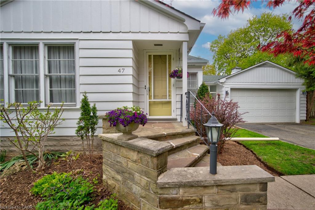 White siding exterior featuring a covered front entry, stone-clad steps, and an attached garage with a panel door