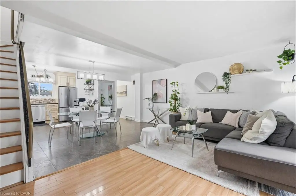Open-concept interior featuring wood-finish flooring, large-format tile flooring, a built-in staircase with a metal railing, and stainless-steel kitchen appliances