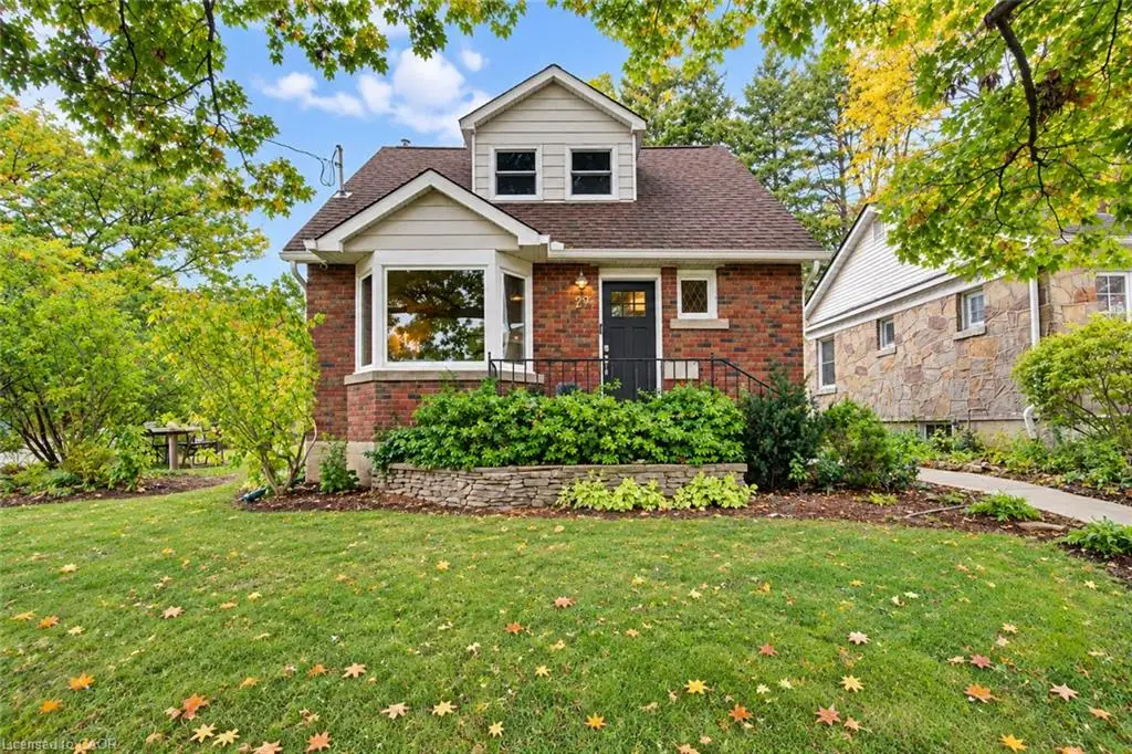 Brick and Maibec exterior featuring a prominent bay window, gabled roofline, stone retaining wall, and front entry with wrought-iron railing