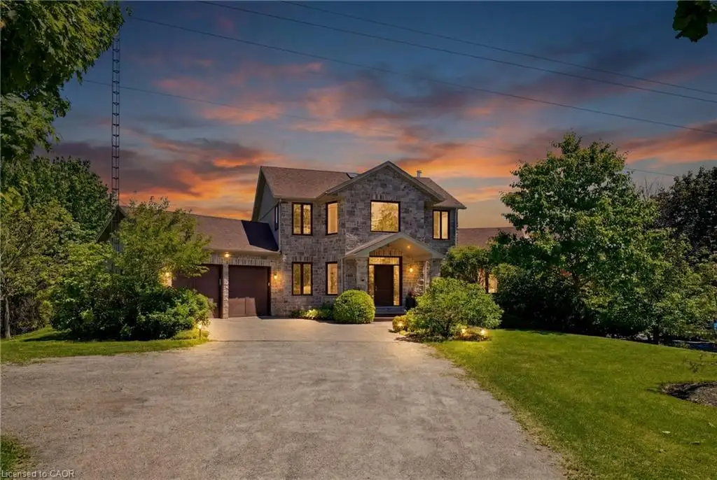 Stone-clad exterior, two-car garage, established landscaping, paved driveway, and covered entry