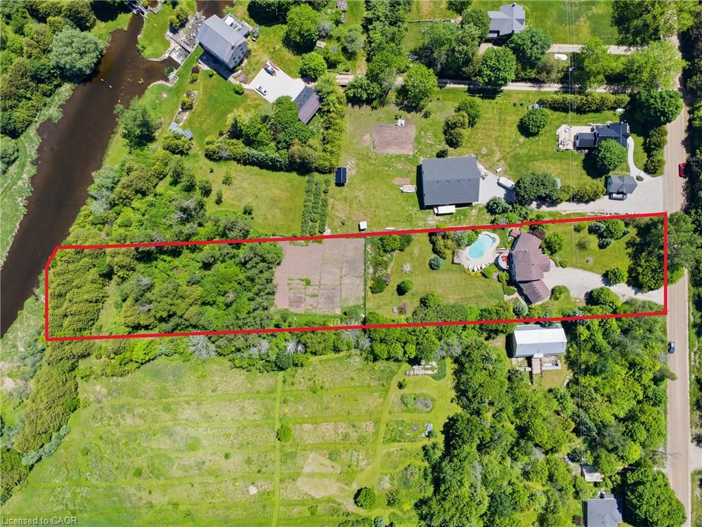 Expansive property featuring a curved swimming pool, multiple outbuildings, wooded areas, and a visible river boundary