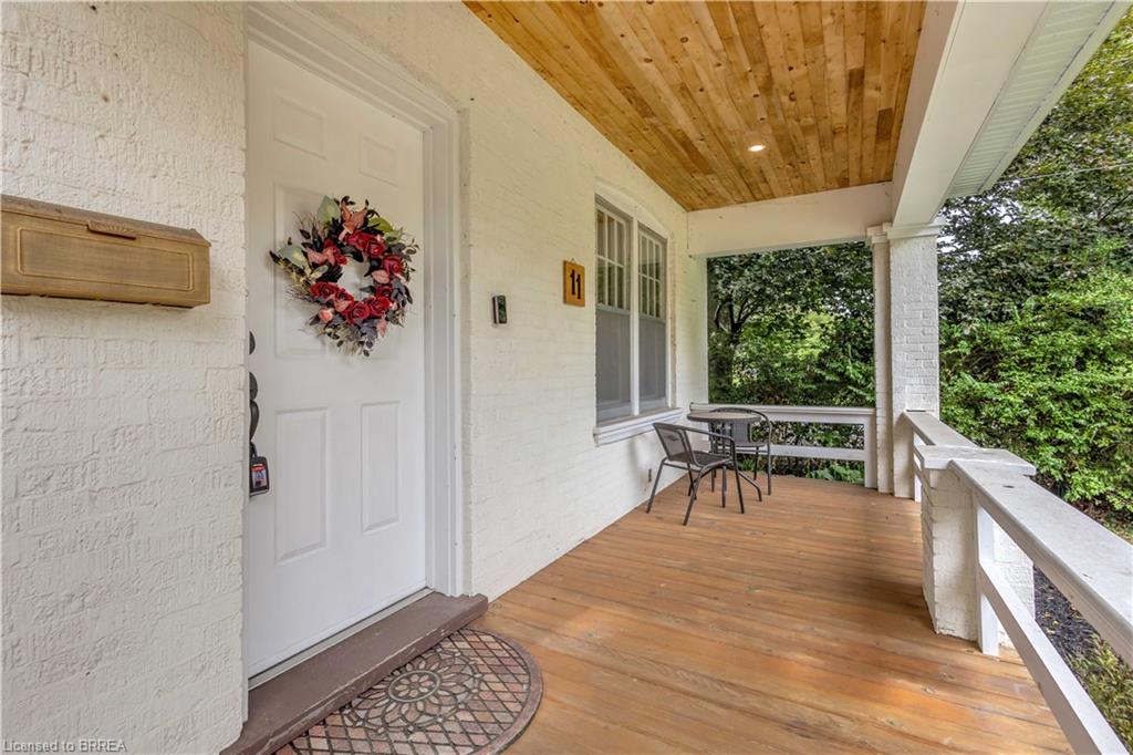Covered porch featuring wood-finish flooring, a white paneled door, and a natural wood ceiling with recessed lighting