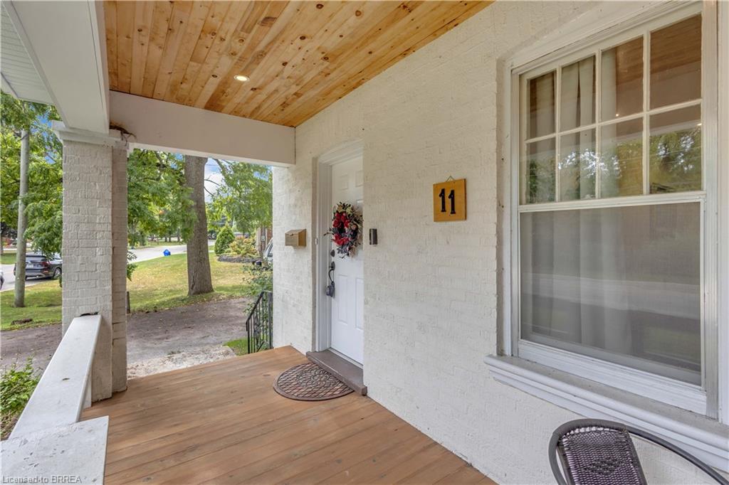 Covered front porch featuring a wood-finish ceiling with recessed lighting, exposed brick pillars, and wood-finish flooring