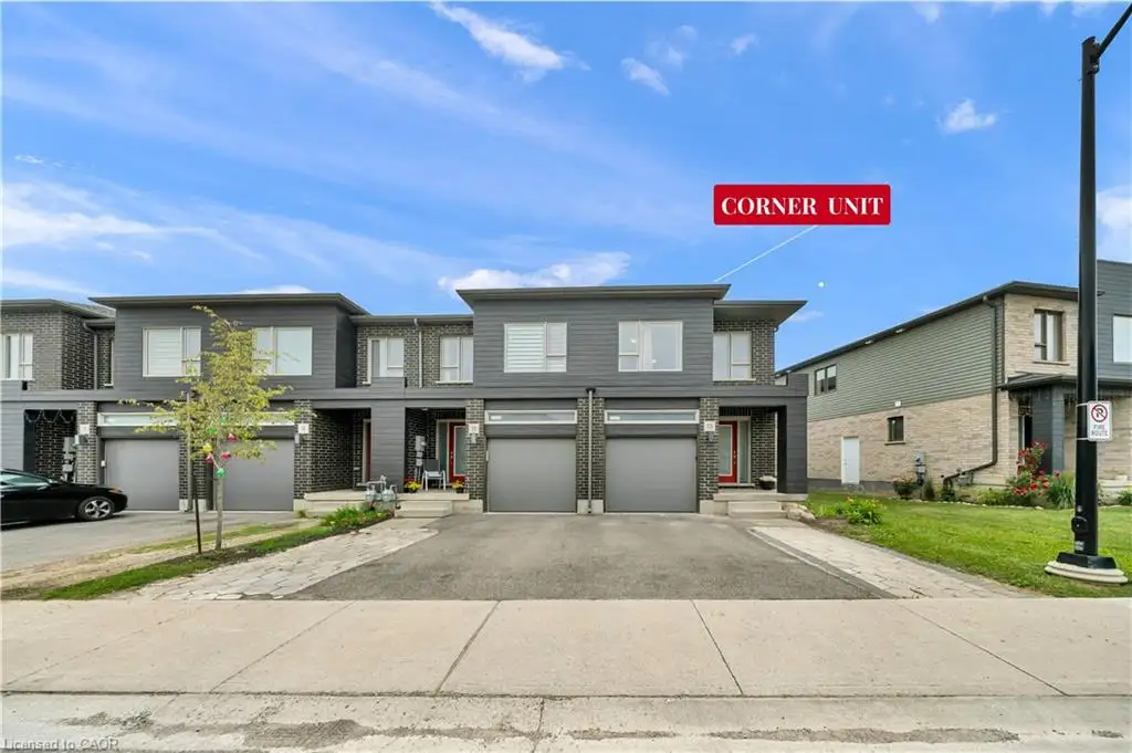 Contemporary townhome with a dark gray facade, brick accents, integrated garage, and private driveway