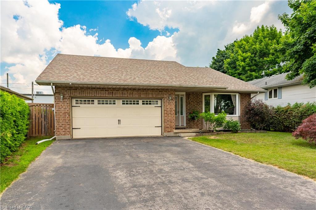 Brick facade home featuring an attached single-car garage, a paved driveway, and a bay window