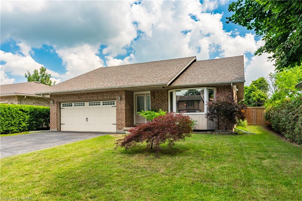 Brick exterior featuring an attached two-car garage with overhead door, paved driveway, and a front bay window