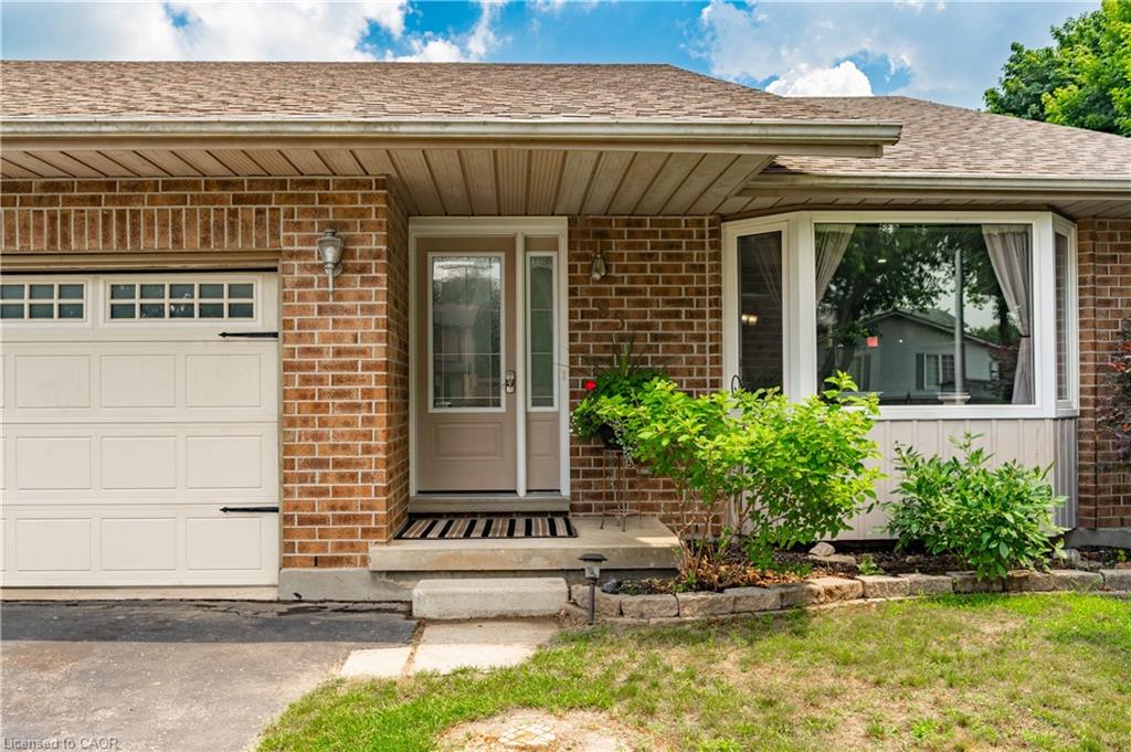 Brick exterior featuring an attached garage with decorative hardware, a bay window, and a front entry with sidelight
