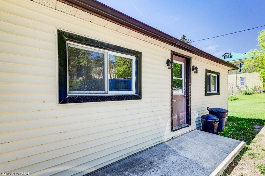 Side exterior with light-toned siding, dark trim windows, and a dark-toned entry door