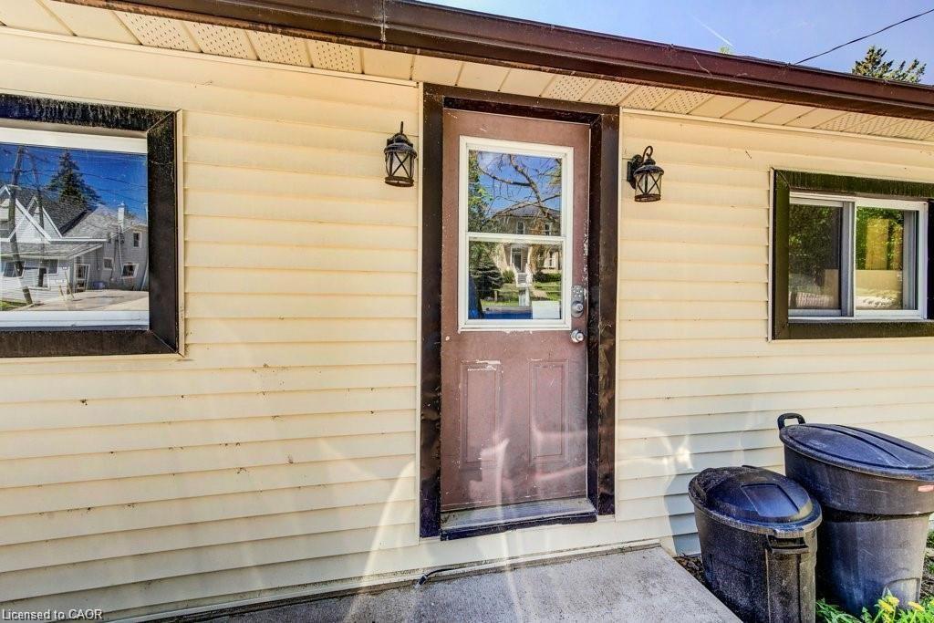 Cream vinyl siding exterior with a brown door featuring a window panel, flanked by two black lantern-style wall sconces