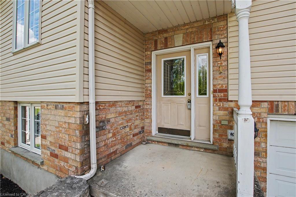 Entryway featuring brick and siding facade, an ornate exterior light fixture, and decorative glass door inserts