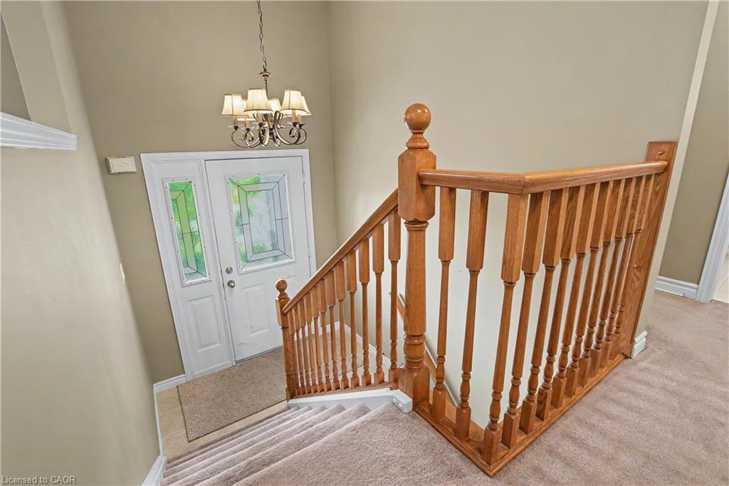 Entryway featuring a decorative transom, a wood-finish staircase railing, and a five-light chandelier