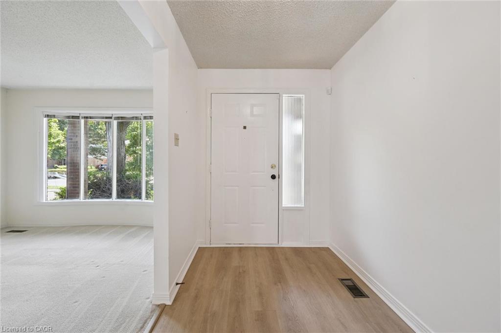 Entryway featuring a white door with a frosted sidelight, wood-finish flooring, and white baseboards