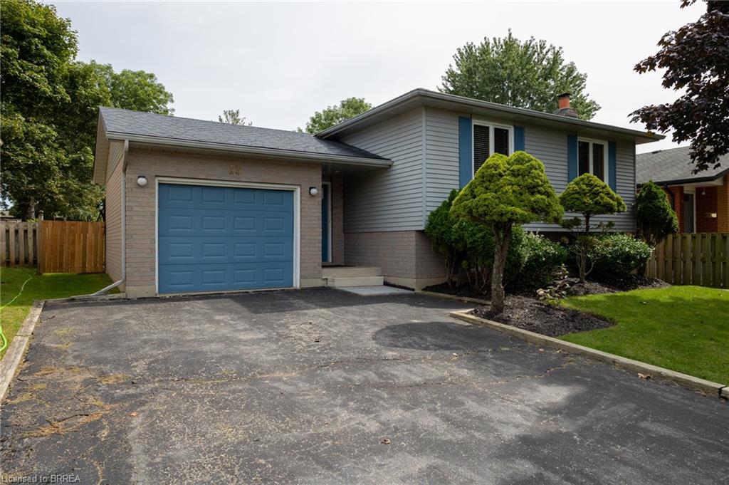 Attached garage with blue door, gray siding, and manicured landscaping
