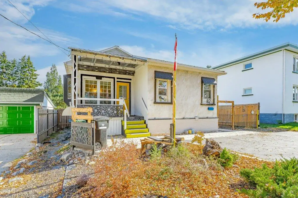 Stucco exterior featuring a covered front porch, multi-pane windows, concrete driveway, and detached garage