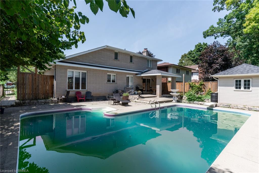 In-ground swimming pool featuring a concrete surround, an adjacent patio, and a covered outdoor living area