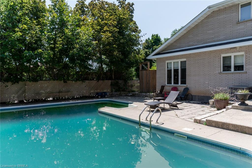 In-ground swimming pool featuring concrete decking, metal handrails, and a surrounding privacy fence