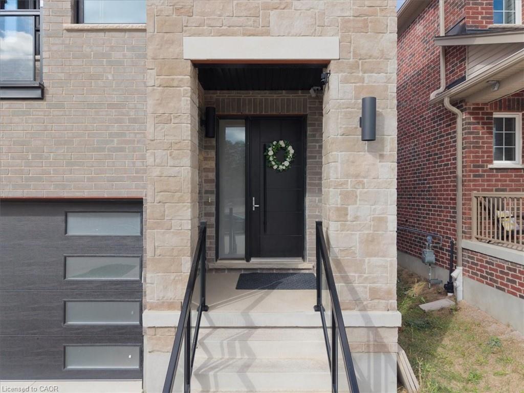 Stone and brick facade featuring a modern black front door with an adjacent sidelight