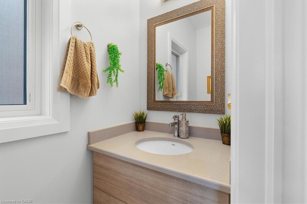 Bathroom vanity featuring an integrated sink, light wood-finish cabinetry, and a framed mirror