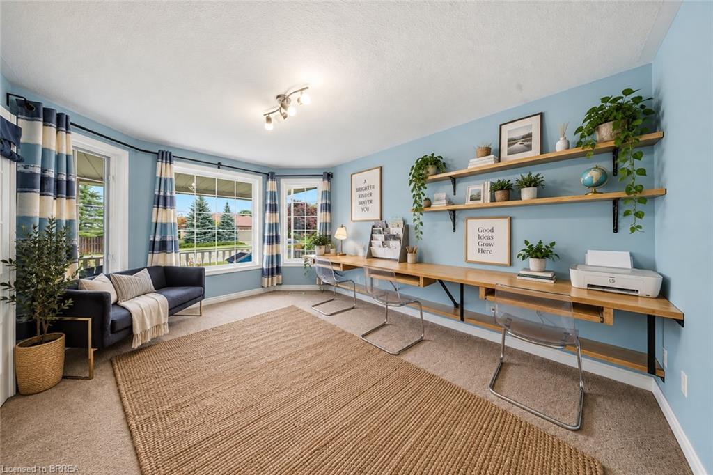 Bay windows, light blue walls, built-in wooden desk, open wooden shelving, and carpeted flooring
