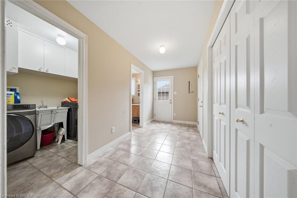 Tile flooring throughout, white bi-fold closet doors, laundry room with built-in cabinetry, utility sink, and washer/dryer hookups, and exterior door with window panes