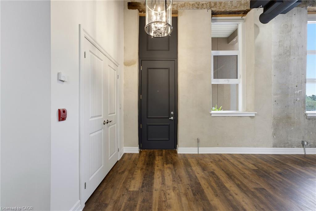 Wood-finish flooring, white trim, modern light fixture, two white paneled doors, and two tall windows