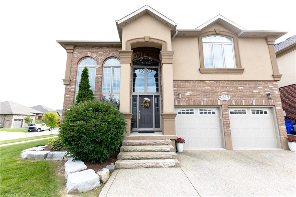 Brick and stucco facade with arched window accents, stone step entry, and dual garage doors