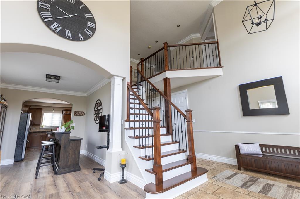 Staircase with wood treads and wrought iron spindles, high ceilings, arched entryway, upper landing, and wood-finish flooring