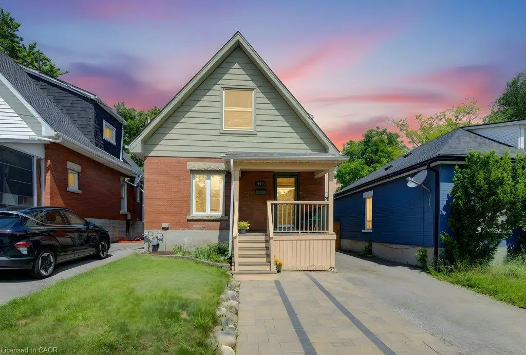 Brick exterior with siding gable, covered front porch with railing, and a paver driveway