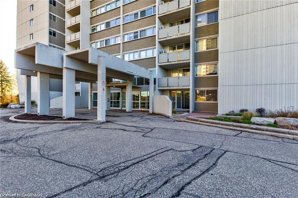 Multi-story residential building featuring a covered entryway with structural columns and a glass-enclosed entrance