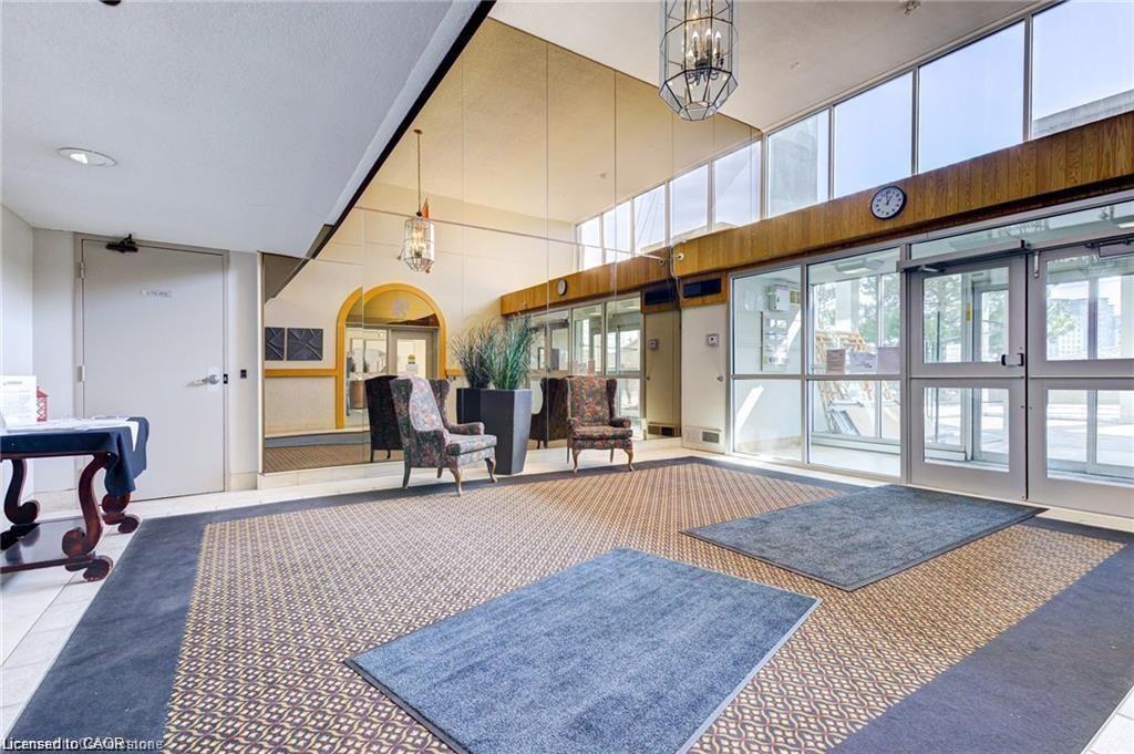 Spacious lobby featuring large windows, patterned carpet flooring, mirrored wall accents, and an arched entry