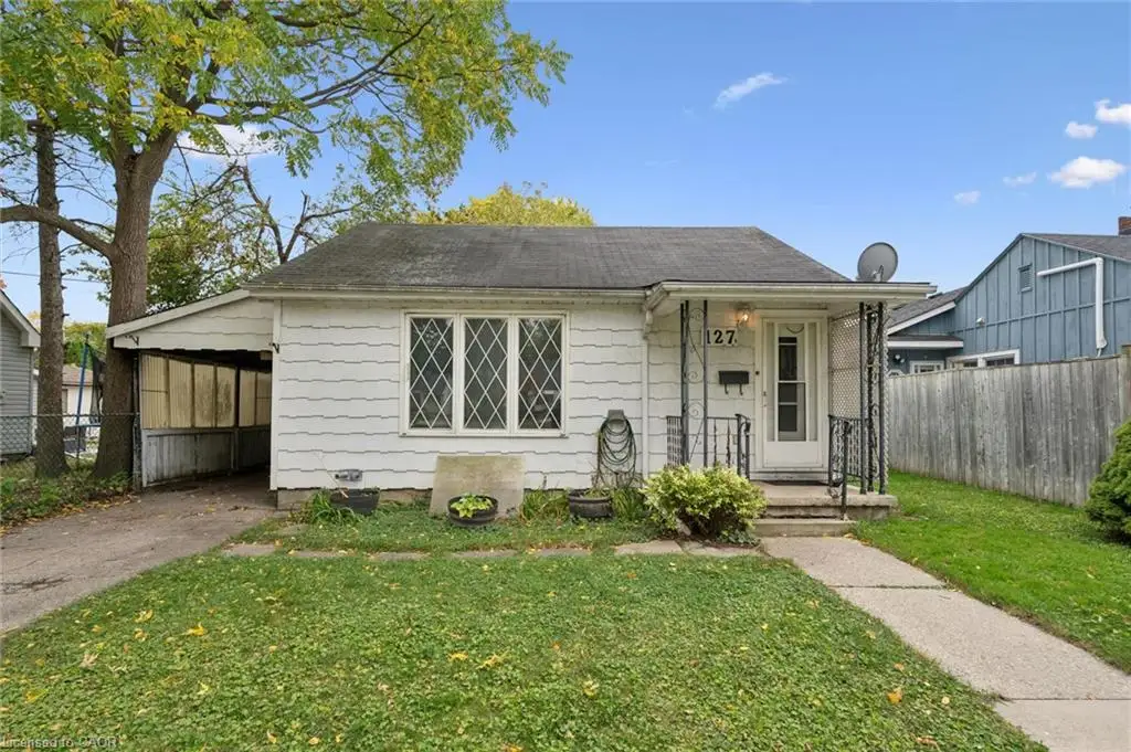 Exterior featuring white siding, a covered carport, diamond-pane window detailing, and a front porch with wrought-iron supports