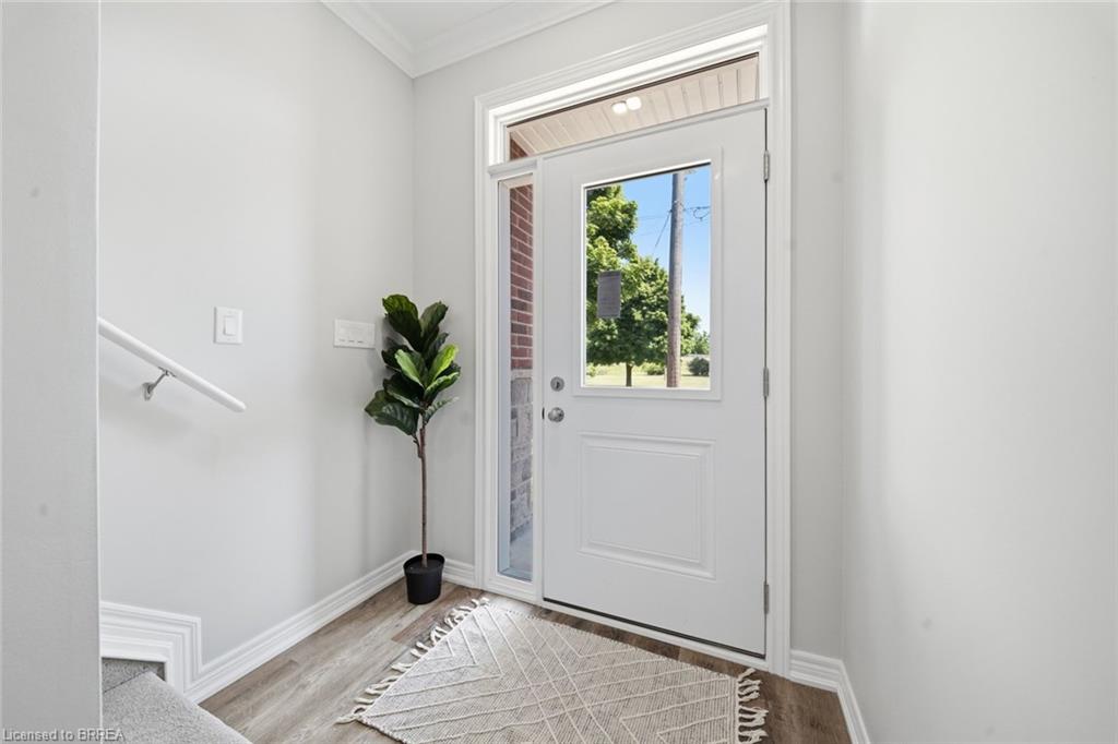 White entry door with a transom window and sidelight, wood-finish flooring, and white baseboards