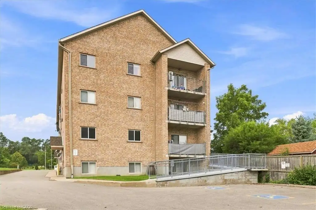 Multi-story brick exterior featuring a metal-railed ramp, three stacked balconies, and paved surface parking