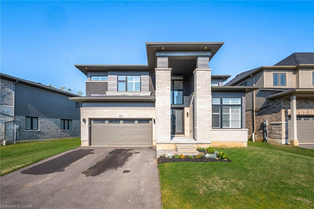 Modern exterior featuring stone and siding finishes, prominent portico with stone pillars, a two-car garage, and a concrete driveway