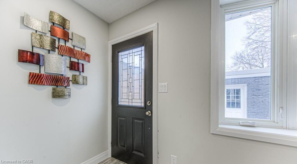 Entryway with a black door featuring decorative glass inserts, a white window frame, and light gray wall paint
