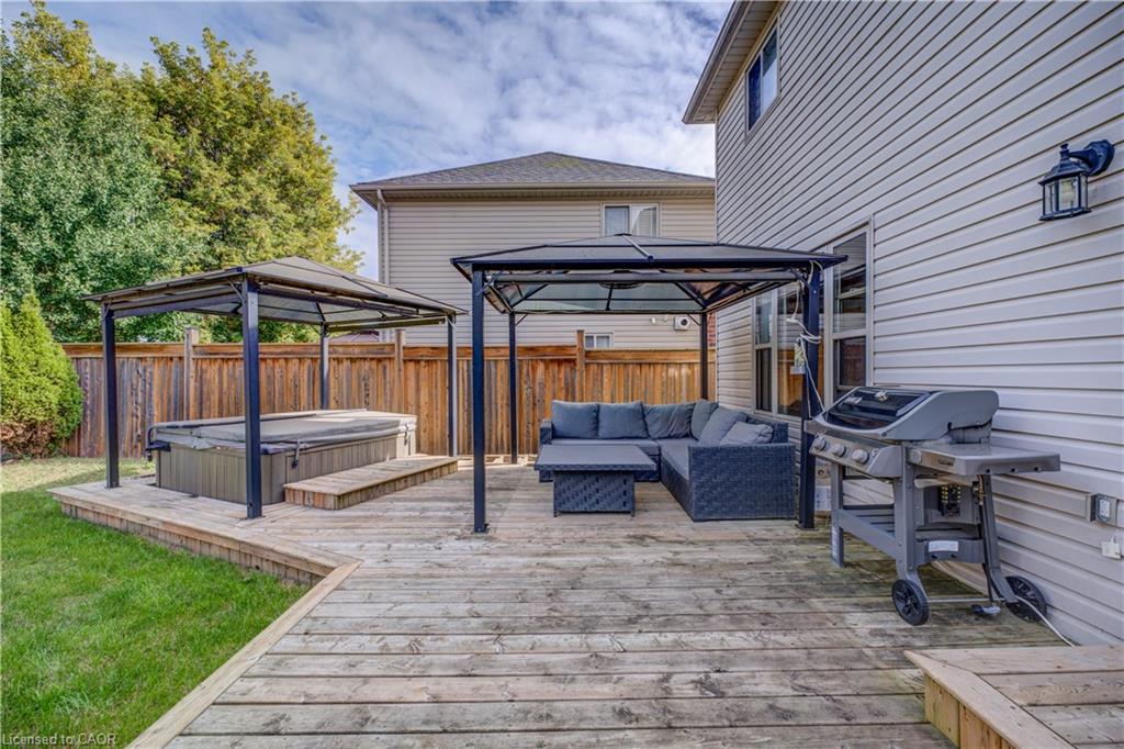 Expansive outdoor deck with a private hot tub, two pergolas, and a wood privacy fence