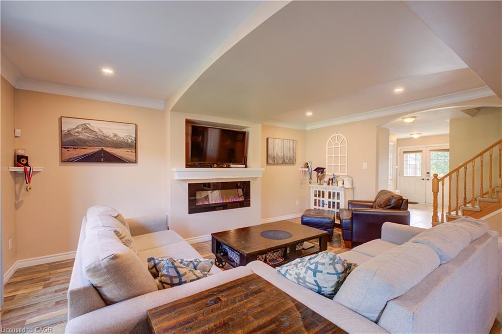 Recessed ceiling lighting, wood-finish flooring, built-in fireplace with mantel, archway architectural detail, and a wood staircase with balusters