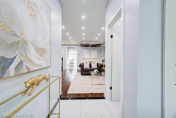 White tile flooring entry leading to a living space with wood-finish flooring, recessed lighting, and a prominent white interior door with black hardware