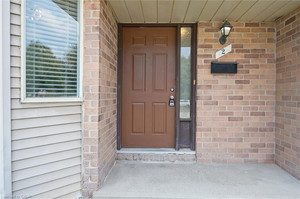 Brick and siding exterior featuring a paneled entry door, sidelight, and an exterior light fixture