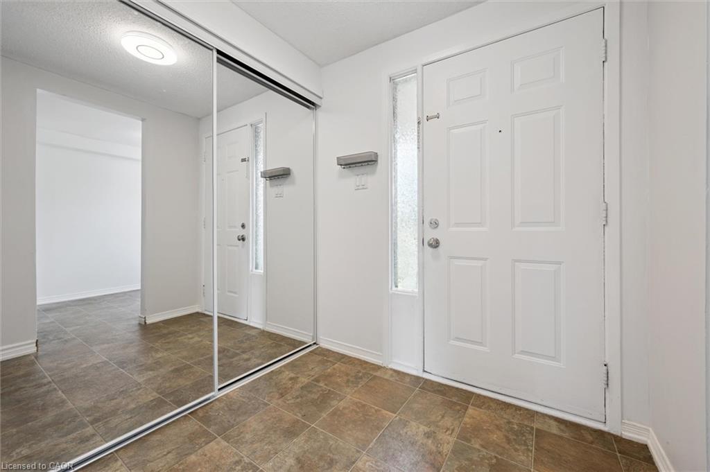 Entryway featuring tiled flooring, a paneled entry door with a frosted sidelight, and a full-height mirrored closet with sliding doors