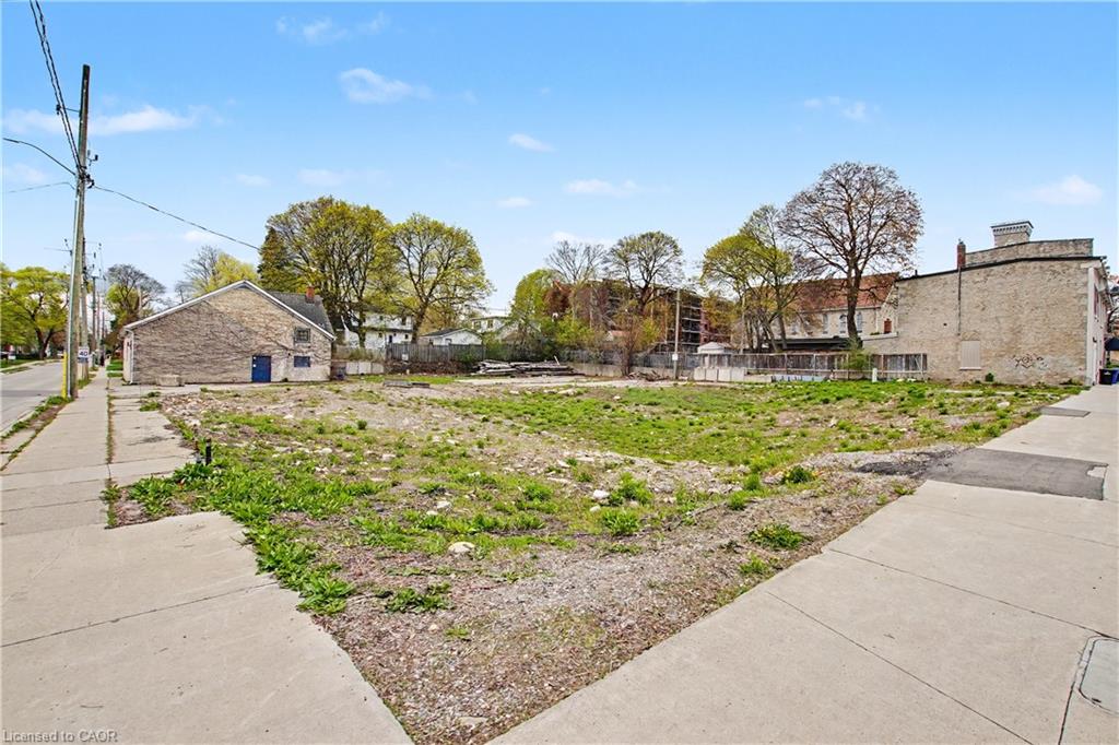 Expansive land parcel featuring existing paved sidewalks and mature trees in the background