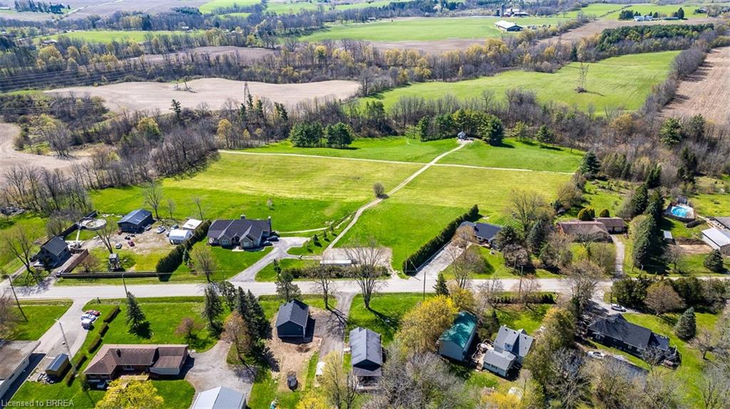 Expansive property featuring a paved road frontage, mature trees, and an additional outbuilding