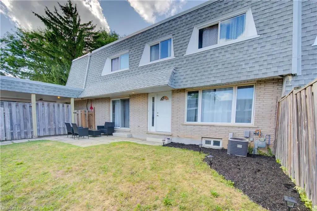 Back of house with mansard roof, a patio area, a fenced backyard, and brick siding