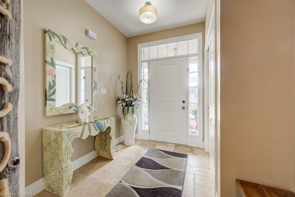 Entryway featuring a white paneled door with sidelights and transom window, light-toned stone-finish flooring, and a flush-mount ceiling light fixture