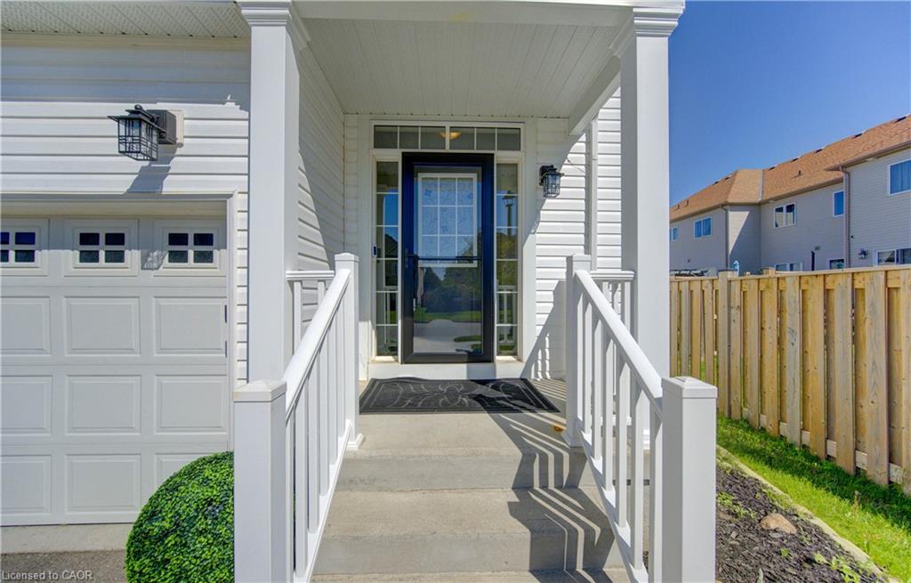 Inviting front entry featuring a covered porch, concrete steps, white railings, and a panelled garage door with square window inserts