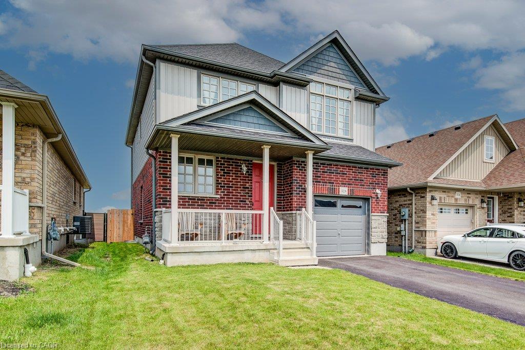 Brick and siding facade with a covered porch, attached garage, and paved driveway