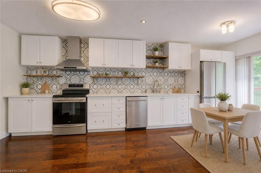 Modern kitchen featuring white cabinetry, stainless steel appliances, patterned tile backsplash, and wood-finish flooring