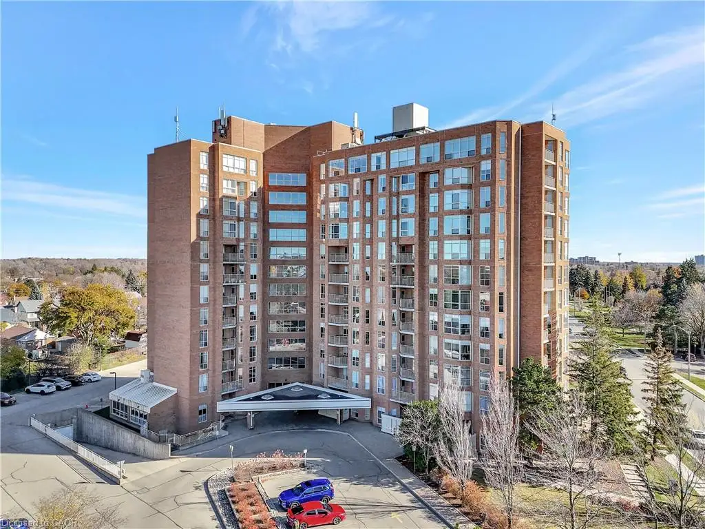 Brick-clad high-rise building with multiple balconies, a covered main entrance, and surrounding paved driveways
